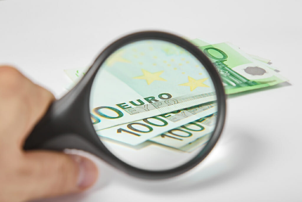 Banknotes Spread Out on a Table With Magnifying Glass